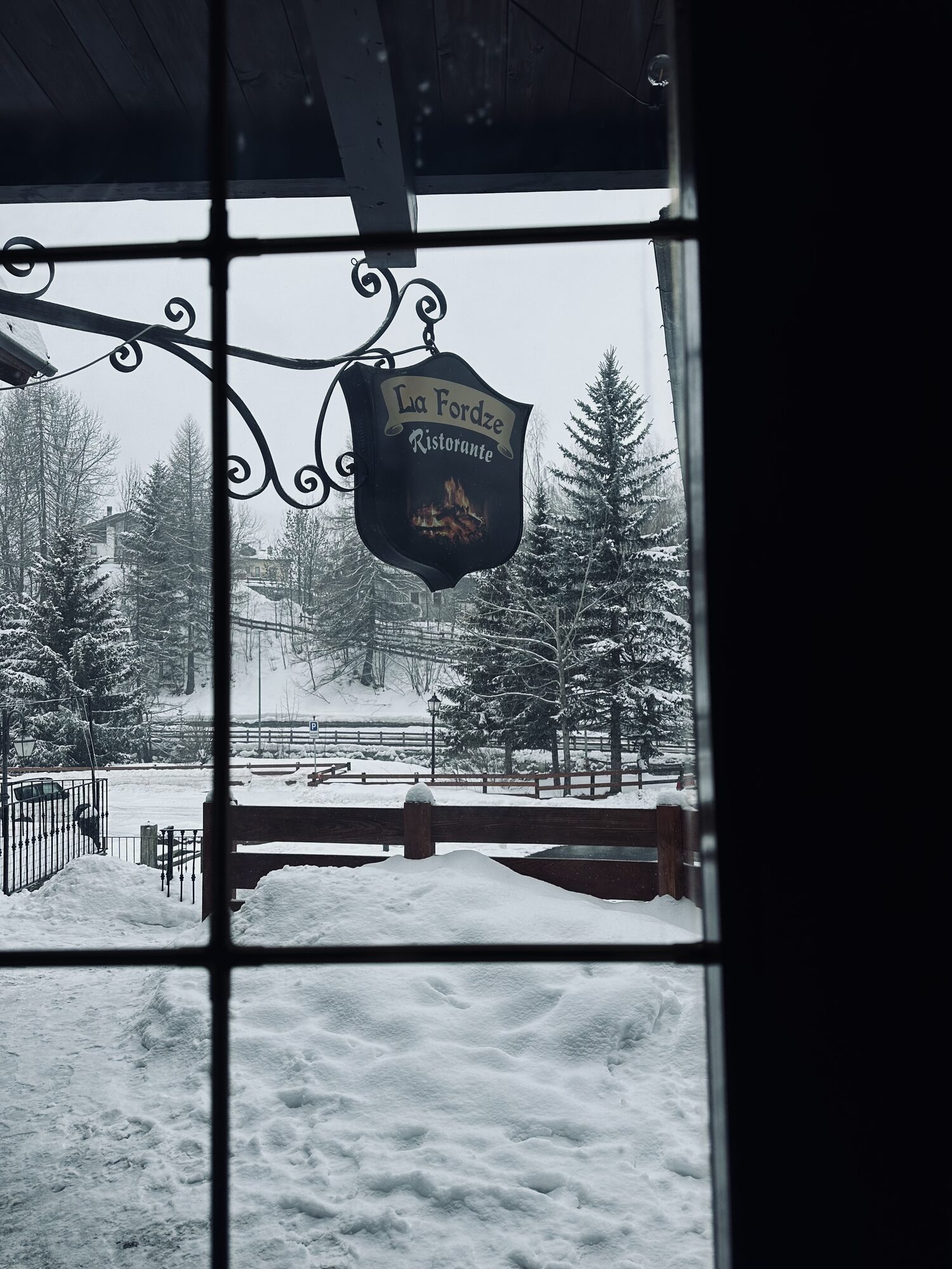 L'insegna del Ristorante La Fordze vista attraverso la finestra innevata di La Thuile