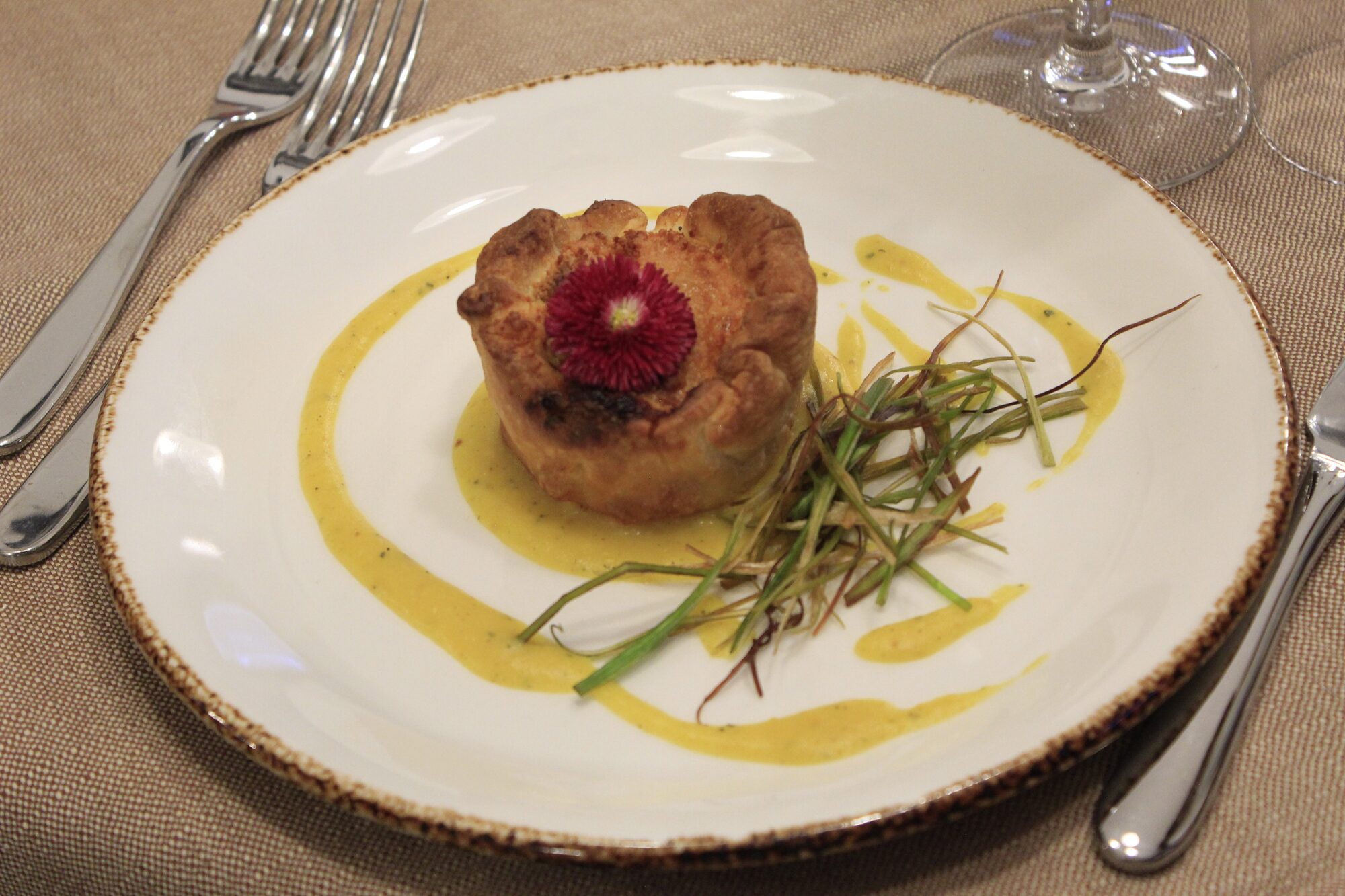Soufflé salato con fiore commestibile su crema allo zafferano