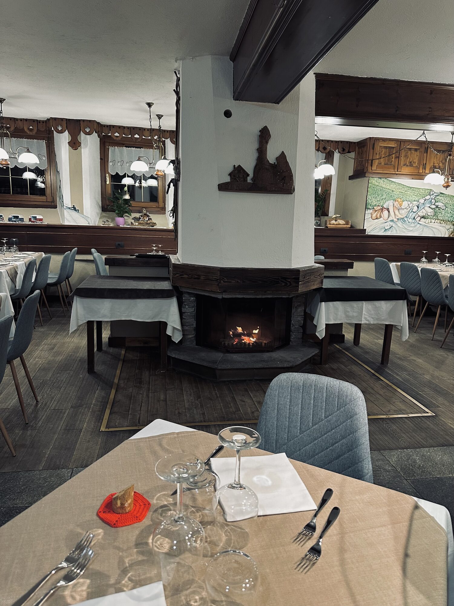 La sala del Ristorante La Fordze con il caminetto acceso e i tavoli apparecchiati